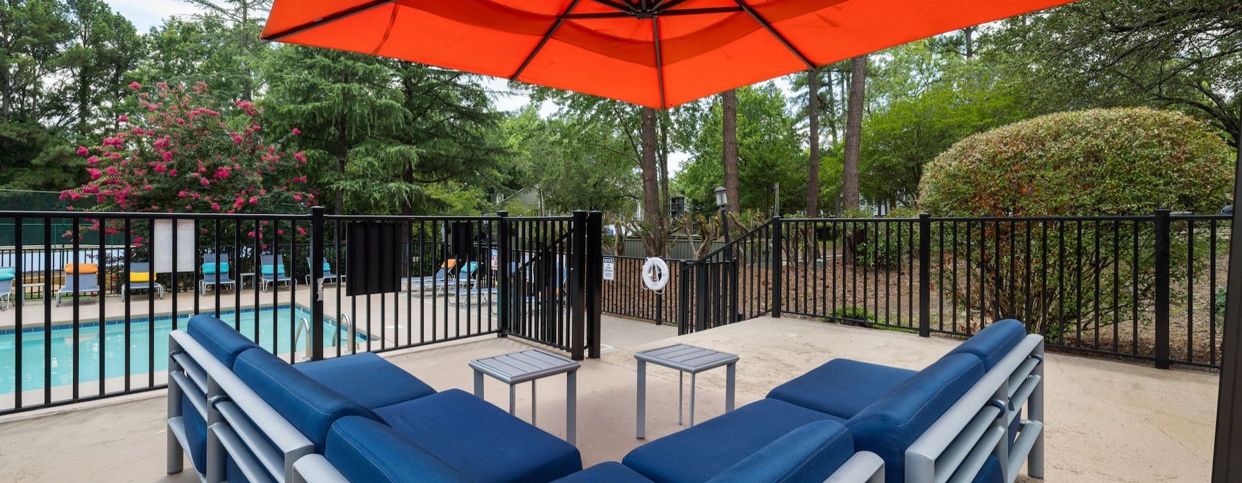 a couple of blue benches sit under an orange umbrella