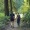 a man and a woman walking on a trail surrounded by trees