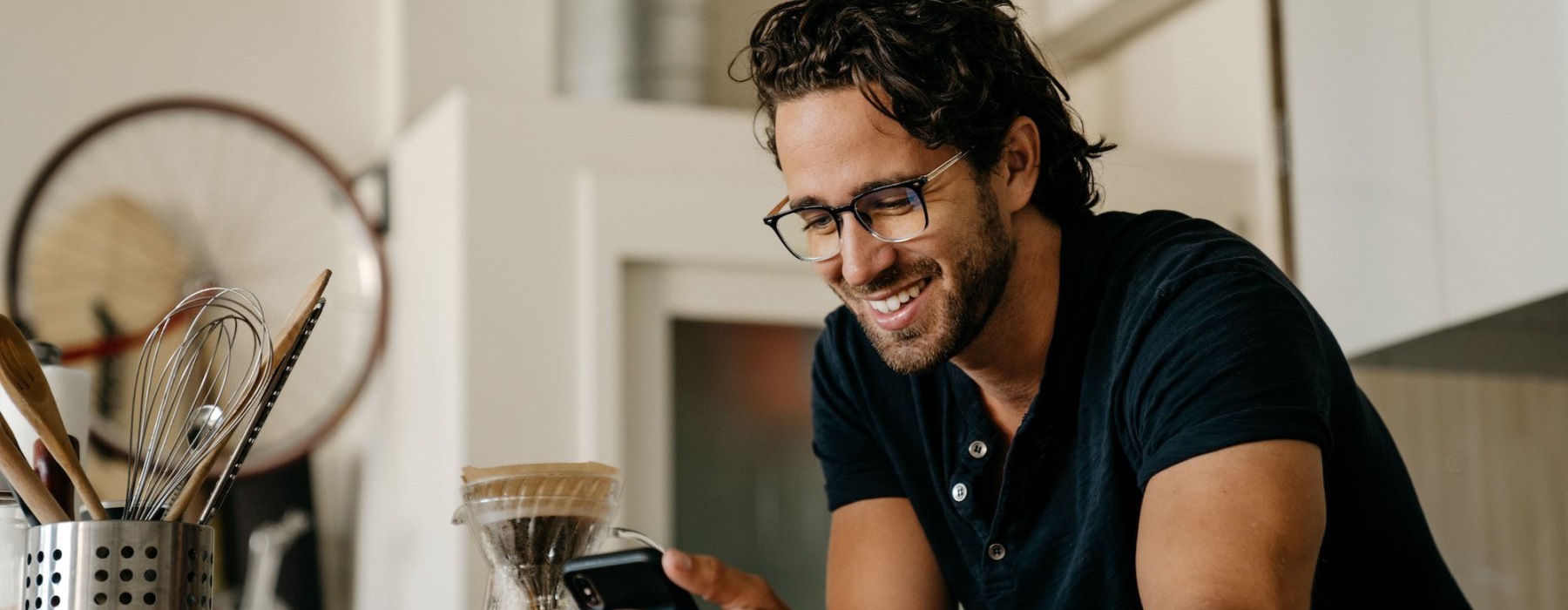 a man smiles as he looks at his phone